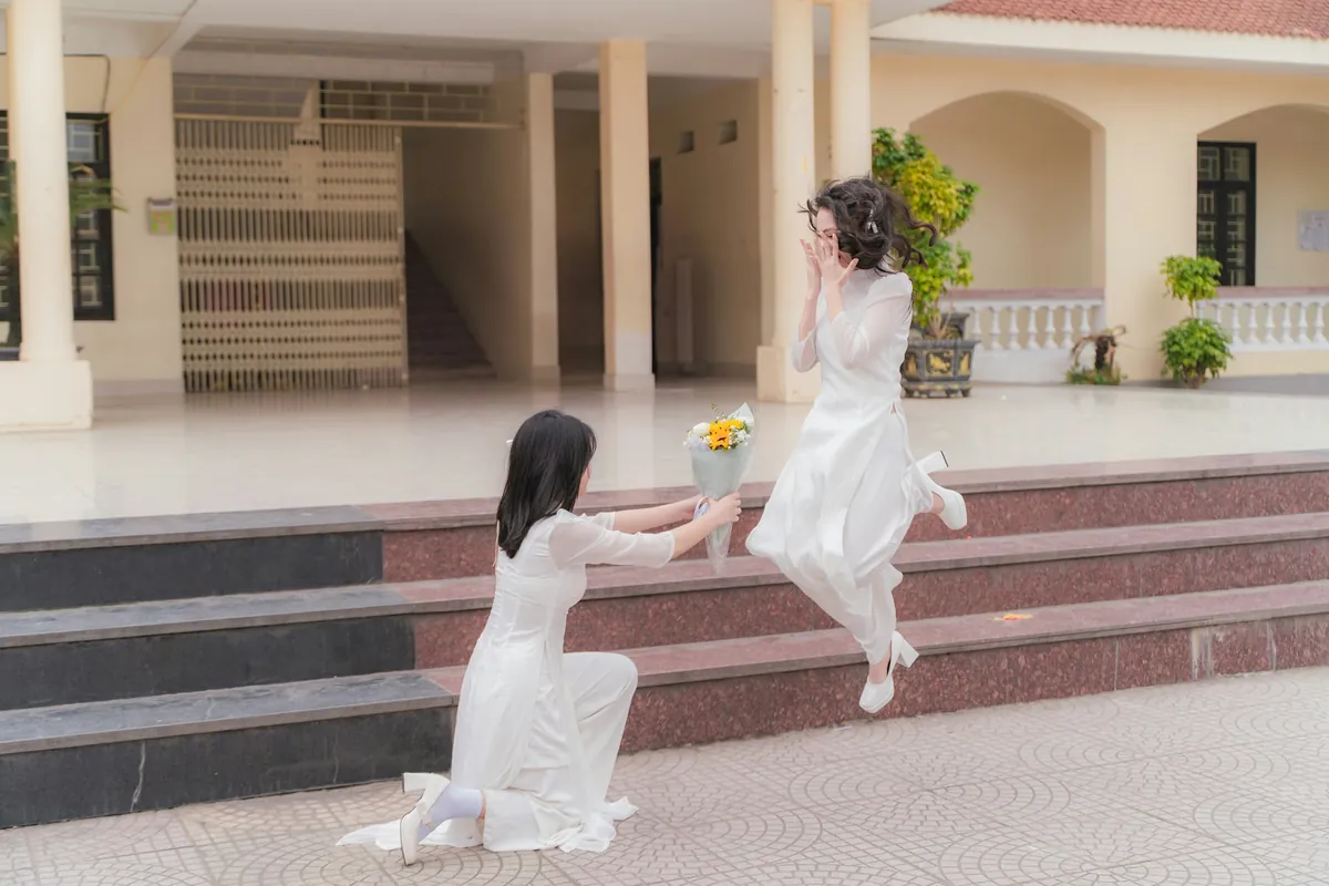 Hai học sinh áo dài bên bậc thềm trường