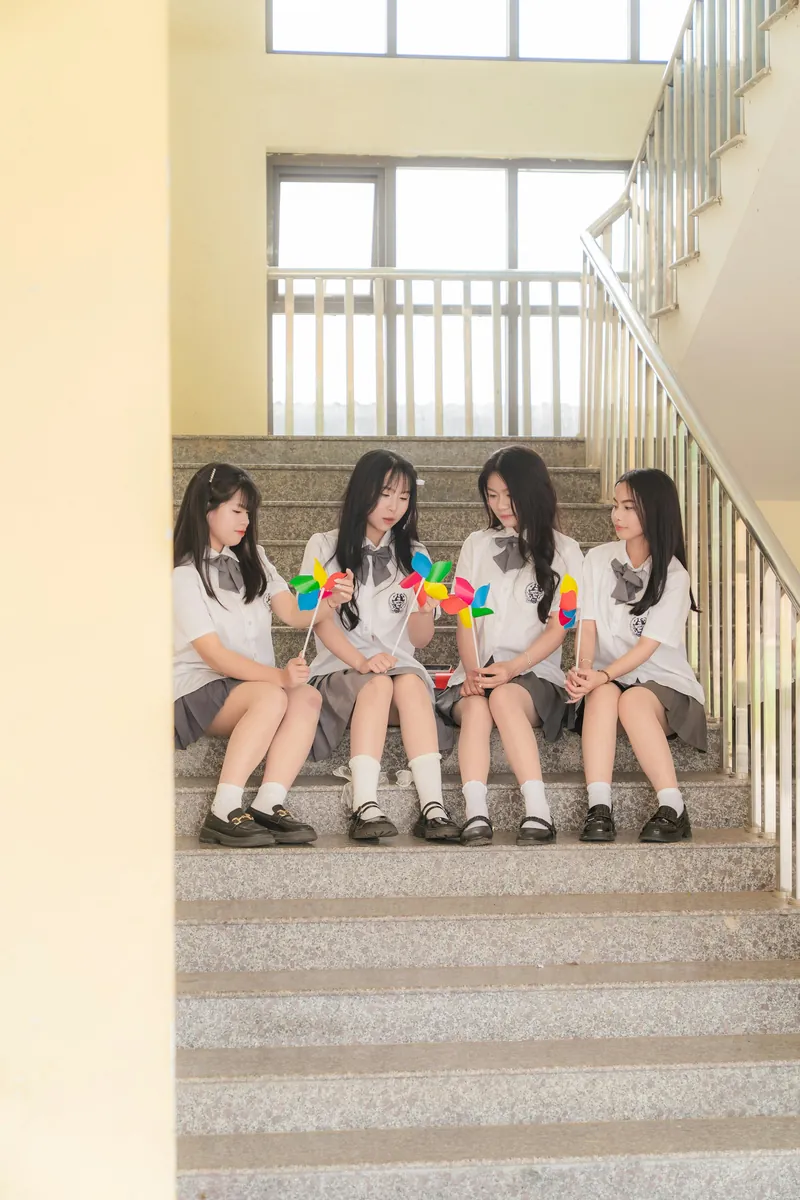 Các bạn nhỏ ngồi trên bậc thang cầm chong chóng