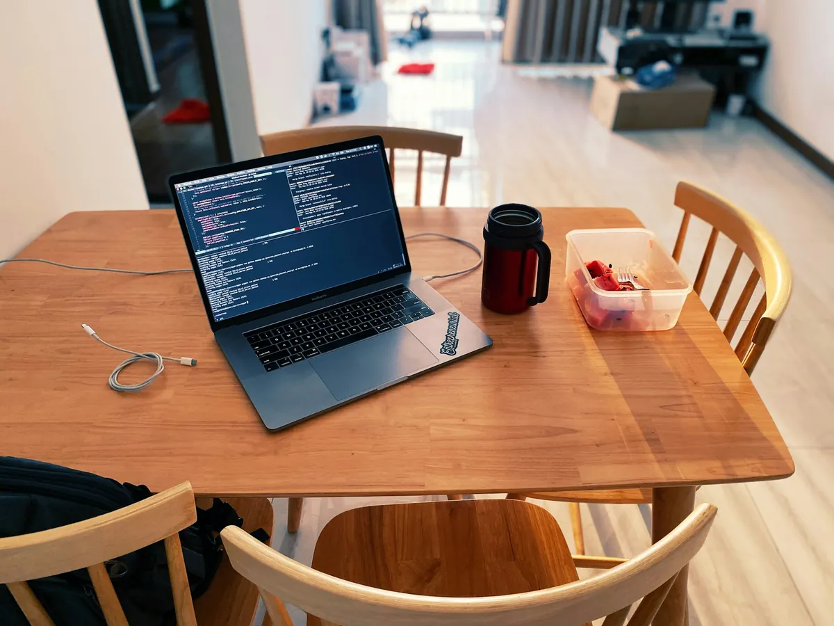 Laptop hiển thị mã nguồn trên bàn gỗ